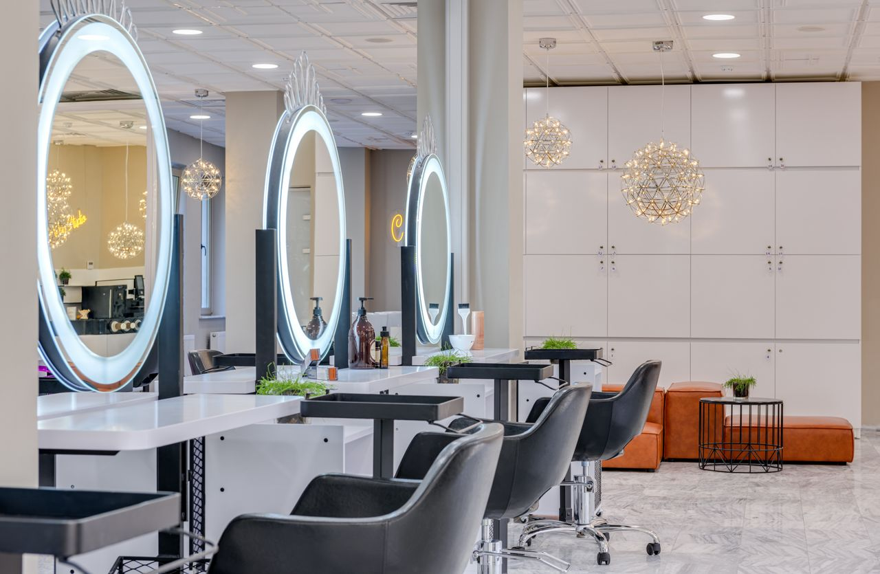 About Bright and elegant hair salon interior featuring modern lighting and round mirrors for a chic and relaxing atmosphere.